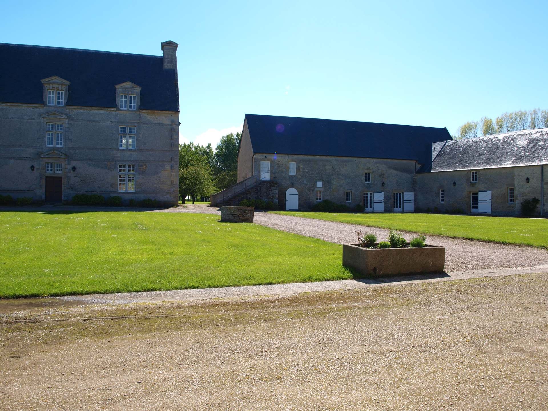 Utsikt över Grande Ferme de Crépon, en historisk normannisk gîte med en grön park och 1700 -talsbyggnader.