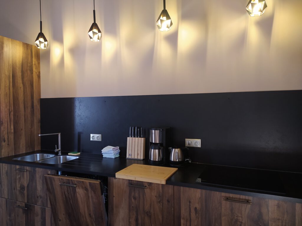 Modernt och varmt köket i Le Colimçon Gîte, med modern utrustning och designbelysning.