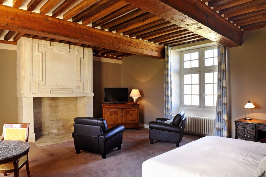 Inre av Gîte le Colimçon i Grande Ferme de Crépon, med öppen spis, trämöbler och varm atmosfär.
